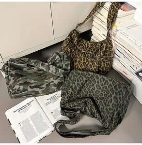 Three canvas messenger bags in leopard and camo prints styled in a cozy indoor setting