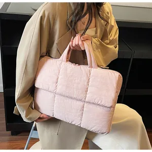 Detail of light pink quilted tote bag showing soft padded nylon texture and top handle
