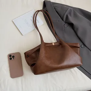 Vue à plat d'un sac cabas vintage marron plissé avec accessoires de bureau élégants