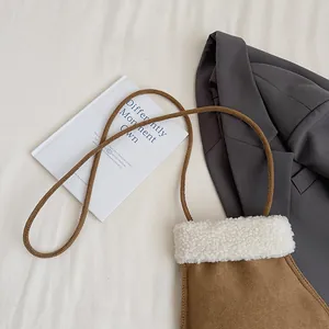 Vue détaillée d'un sac bandoulière en daim marron avec bordure en peluche blanche douce