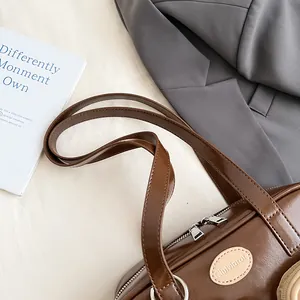 Detailaufnahme der dunkelbraunen Ledertasche mit silbernen Reißverschlüssen und Logo