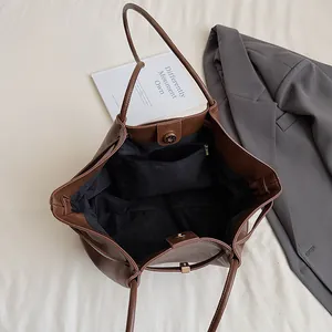 Détail du fermoir magnétique et de la poche zippée du grand sac fourre-tout brun