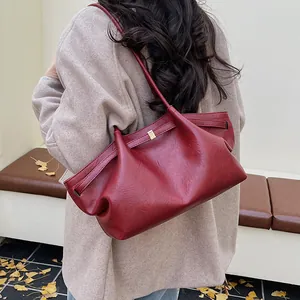 Modèle portant un grand sac cabas bordeaux vintage avec plis en cuir et détails dorés
