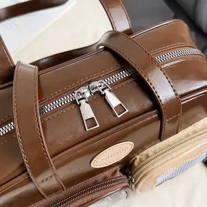 Detail einer dunkelbraunen Leder-Umhängetasche mit Silberreißverschlüssen und Seitentasche