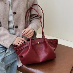 Détail du sac cabas bordeaux en similicuir huilé avec plis élégants et boucles dorées