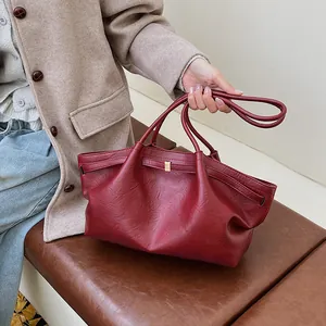 Détail d'un sac cabas bordeaux vintage en similicuir texturé avec boucle dorée
