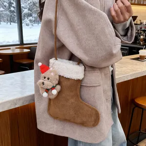 Détail du sac bandoulière en forme de botte de Noël avec breloque peluche dans un café