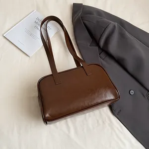 Detailansicht der dunkelbraunen glänzenden Lederstruktur einer minimalistischen Tasche