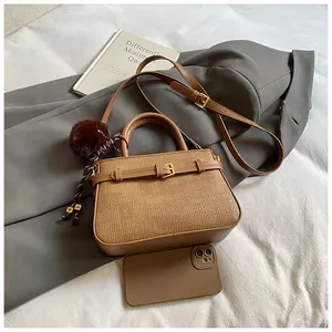 Detail of a brown woven bucket bag featuring a plush charm and a matching phone case