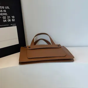 Detailed macro view of the brown leather briefcase with double handles and front pocket