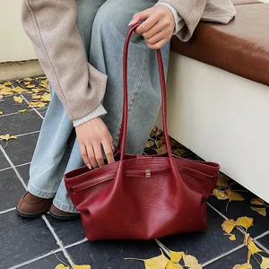 Détail du sac cabas vintage bordeaux en similicuir texturé posé sur un banc de parc