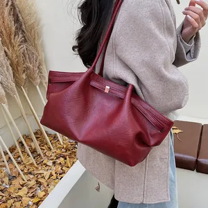 Détail du grand sac cabas bordeaux avec texture en cuir premium et boucle dorée à l'avant