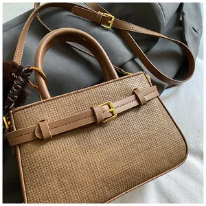 Detail of woven texture bucket bag with gold buckle and brown faux fur pompom charm