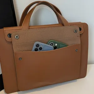 Detailed view of the brown leather briefcase front pocket showing dual smartphone storage