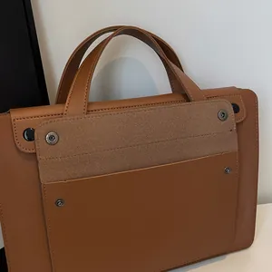 Detailed close-up of brown leather briefcase with matte flap pocket and silver buckle