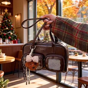 Detail der dunkelbraunen Ledertasche mit transparenter Tasche und Plüsch-Pudel-Anhänger