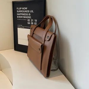Detail view of caramel brown leather briefcase featuring multi-layer storage and metal buckle