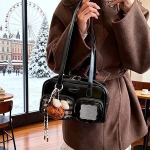 Detail der schwarzen Lackleder-Umhängetasche mit Karotaschen und Plüschbär-Anhänger