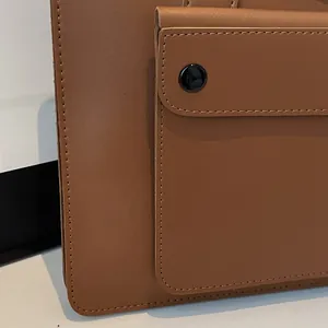 Close-up of brown leather briefcase featuring front flap pocket and black snap button