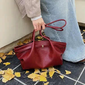 Détail d'un sac cabas bordeaux en similicuir avec plis souples sur fond d'automne