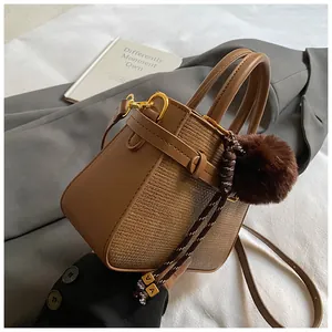 Detail of woven texture contrast and brown leather bucket bag with fur ball charm