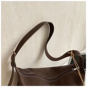 Close-up of brown suede bucket bag featuring contrast white stitching and silver hardware