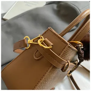 Detail of vintage brown bucket bag showing leather stitching and gold metal hardware