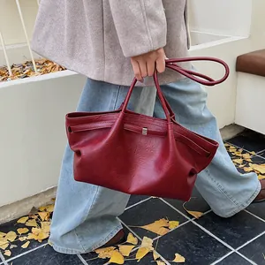 Détail du sac cabas en cuir rouge foncé montrant la texture souple et la boucle