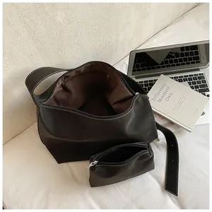 Detail of black leather tote bag with white contrast stitching and a small matching pouch