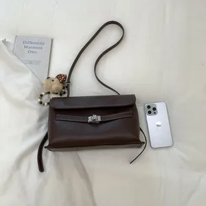 Dettaglio borsa tote vintage marrone scuro con cuciture bianche e ciondolo a cane