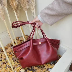 Détail du sac cabas vintage rouge foncé avec texture cuir et boucle dorée élégante