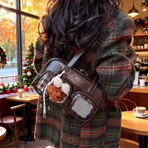 Detail einer braunen PU-Ledertasche mit Teddybär-Anhänger und klarem Taschenfach