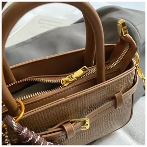 Detail of brown woven leather handbag showing shiny gold hardware and stylish braided lanyard