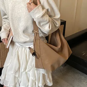 Close-up of brown matte faux leather shoulder bag with wide strap and pleated detail