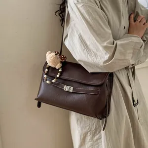 Dettaglio borsa tote marrone vintage con chiusura girevole e ciondolo a orsetto