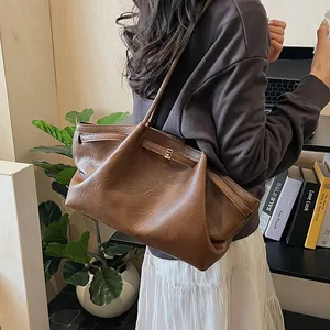 Gros plan du sac fourre-tout rétro marron foncé en cuir mat avec une boucle dorée