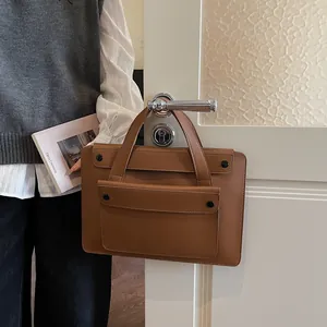 Detailed view of brown leather laptop bag with matte finish and black buckle front pocket