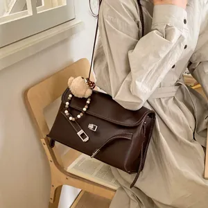 Dettaglio borsa in pelle marrone con chiusura argento, orsetto e catena di perline