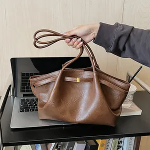 Détail d'un sac cabas vintage marron montrant la texture du cuir et la boucle dorée