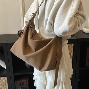 Close-up of brown matte leather hobo bag featuring a unique knotted shoulder strap detail