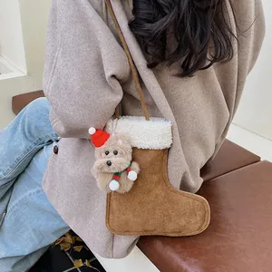 Sac botte de Noël en daim marron avec pendentif chien en peluche porté sur un manteau