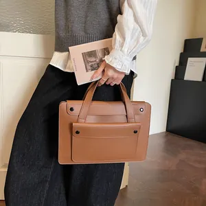 Brown leather business briefcase with snap button front pocket shown in hand