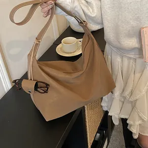 Close-up of caramel brown hobo bag with white stitching detail and glasses holder