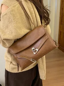 Grande borsa tote retrò marrone con cuciture bianche e fibbie in argento su una modella