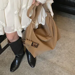 Brown large capacity hobo bag in soft leather styled with sunglasses and white dress