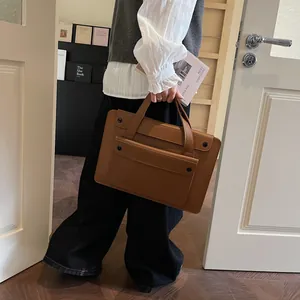 Detail of professional brown leather laptop tote with black buckle and sturdy handle