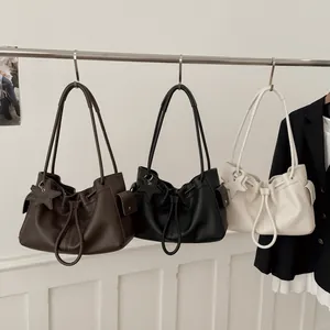 Close-up of three classic tote bags in dark brown, black, and beige with star charms