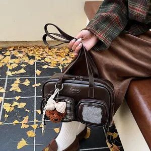 Detailansicht einer dunkelbraunen Retro-Umhängetasche mit Bärenanhänger und Netztaschen