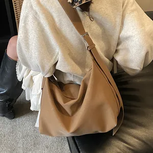 Large brown faux leather hobo bag with silver buckle worn by a model on shoulder