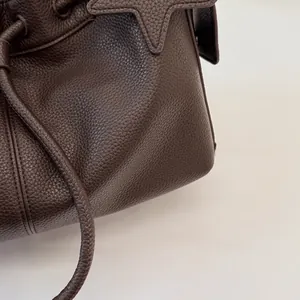 Close-up of dark brown lychee grain leather tote bag with star-shaped patch detail